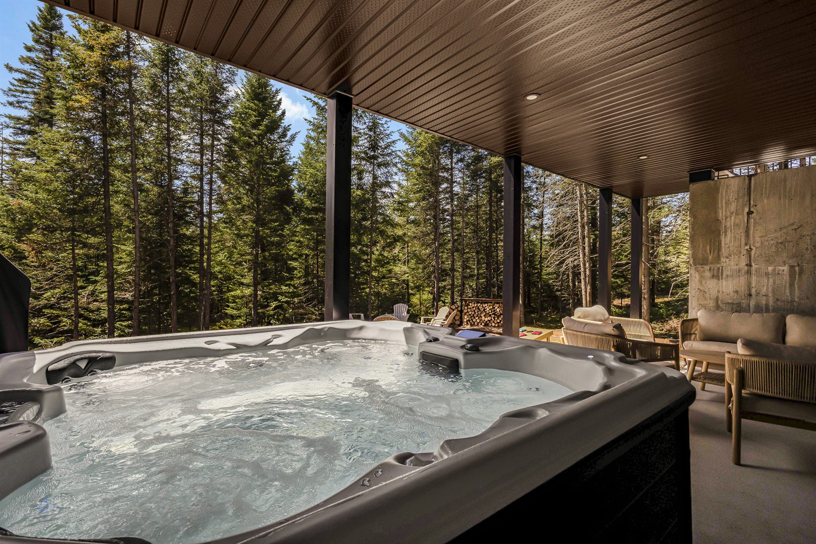 Spa extérieur sous une terrasse couverte avec vue sur la forêt