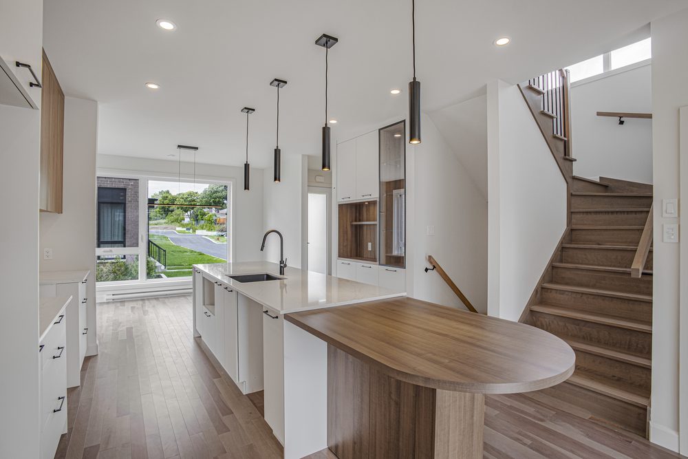 Open-plan area in a new build: kitchen island with quartz counter, wood table and staircase