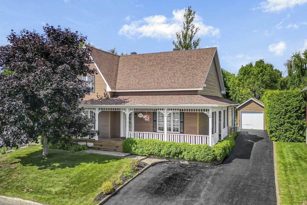 Front of a house with covered porch, landscaping and detached garage