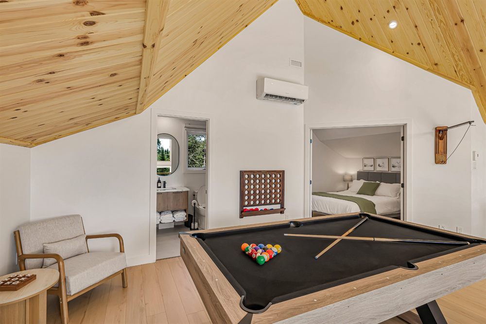 Salle de jeux avec table de billard et plafond cathédrale en bois