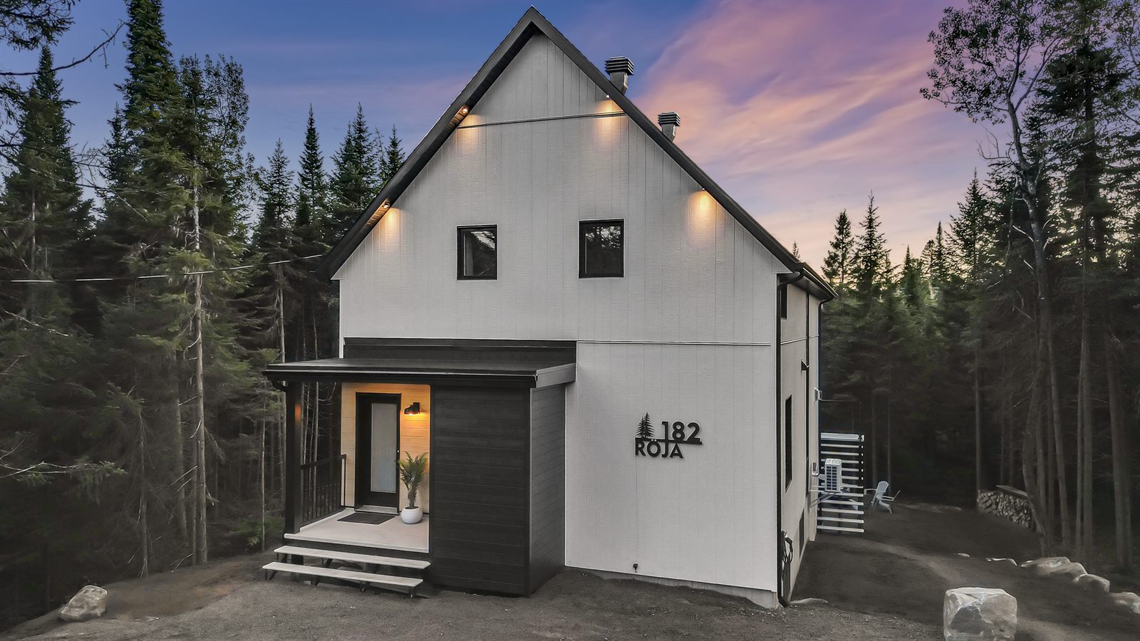 Vue aérienne d'un chalet noir et blanc en forêt au crépuscule