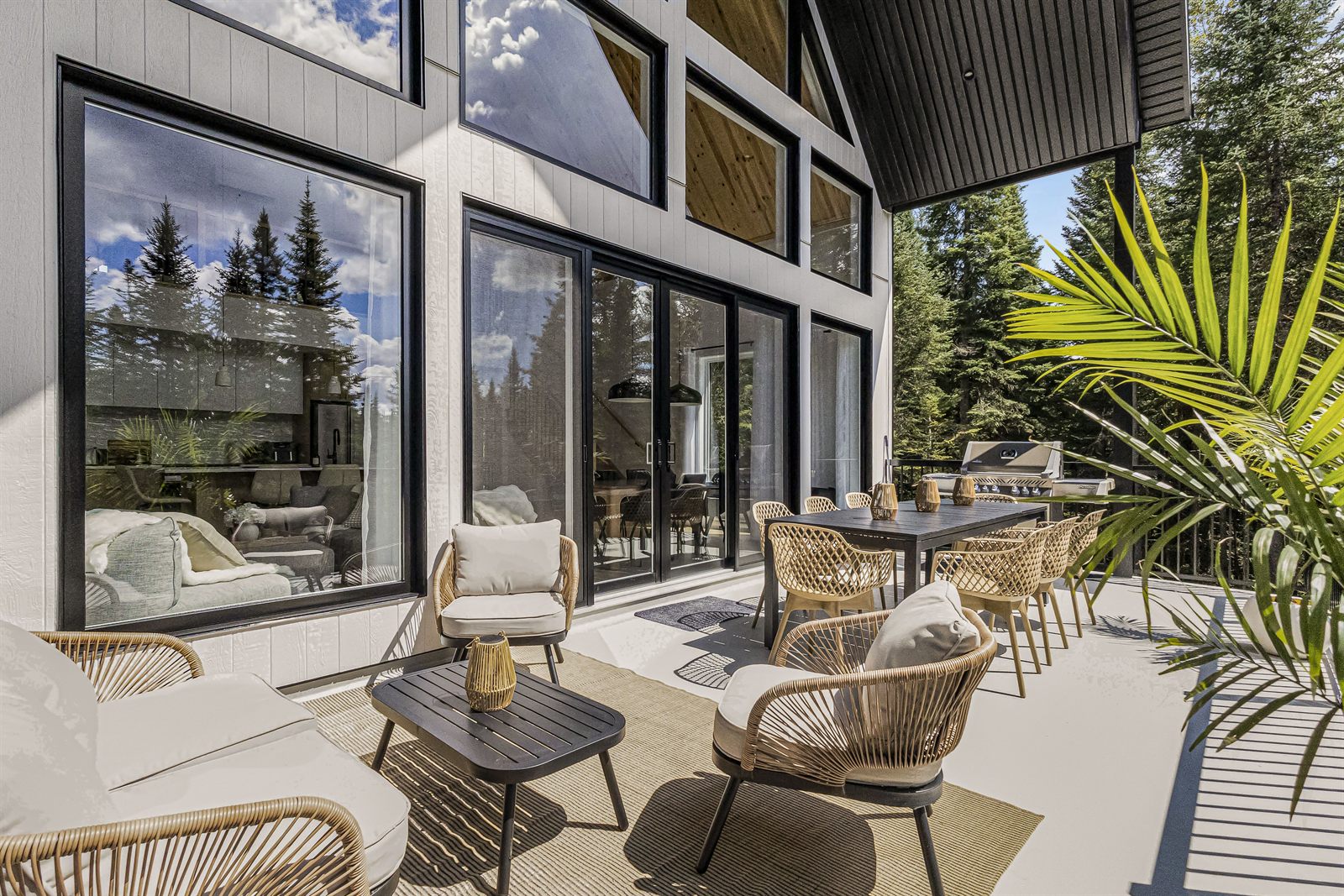 Terrasse avec fauteuils en rotin et table à manger devant de grandes fenêtres